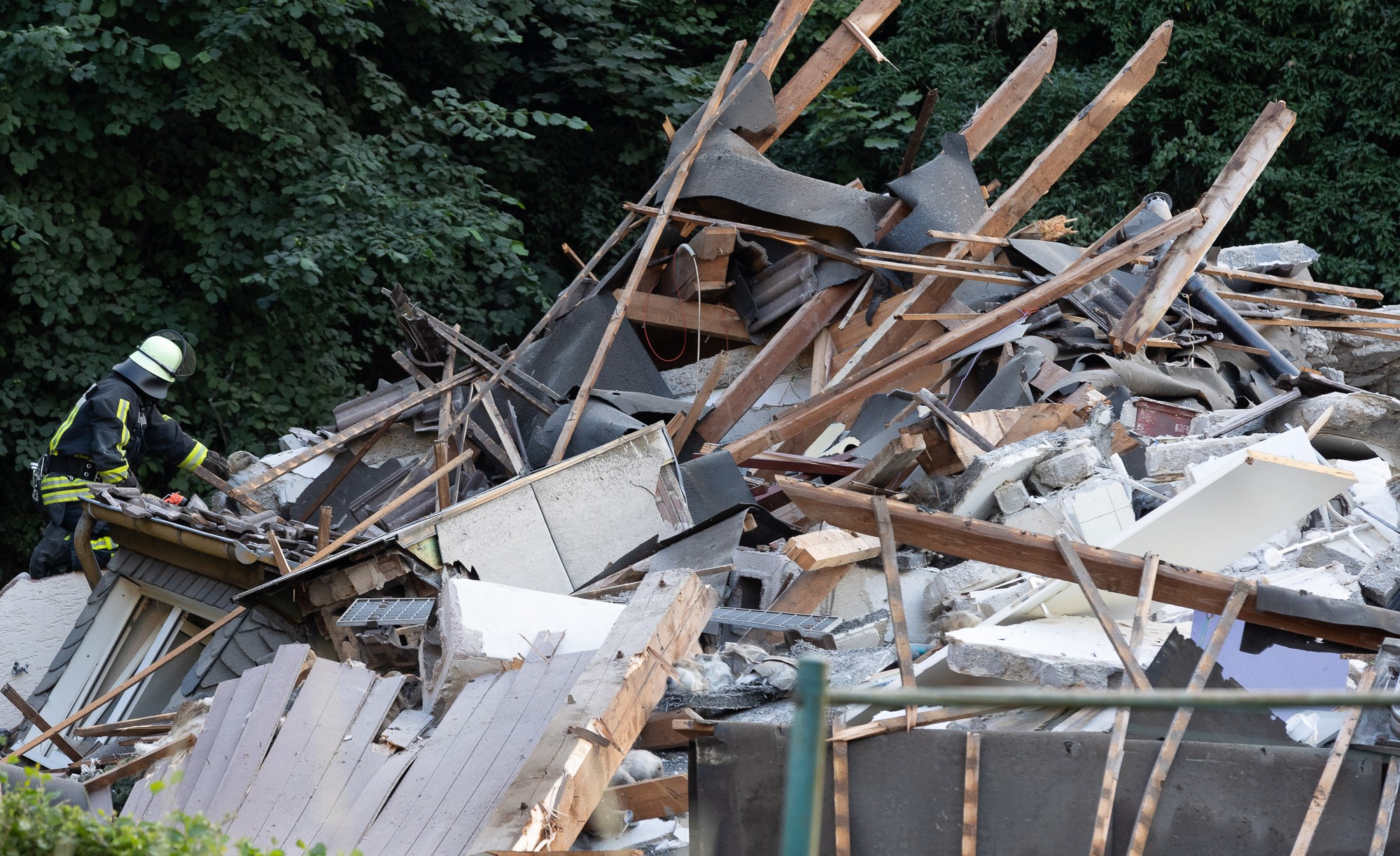 Hasiči skúmajú trosky zrúteneho obytného domu.