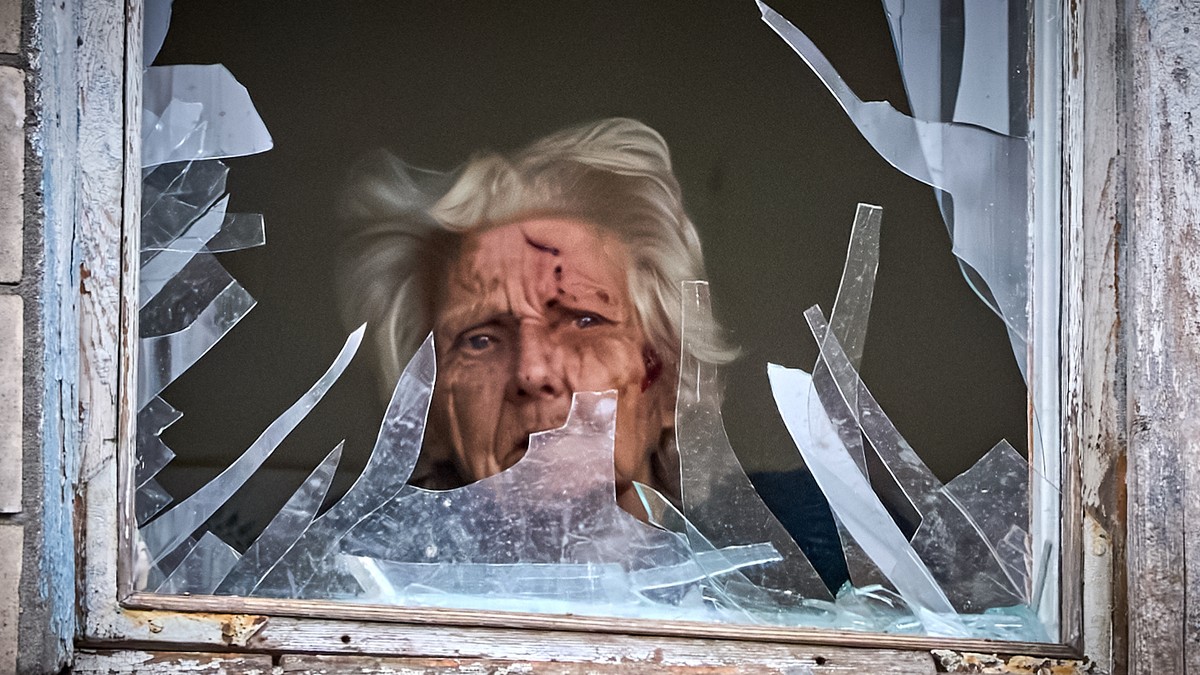 Starija žena gleda kroz razbijeni prozor nakon što je stambenu zgradu pogodio ruski dron tokom vazdušnog napada u Kijevu, decembar 2025.