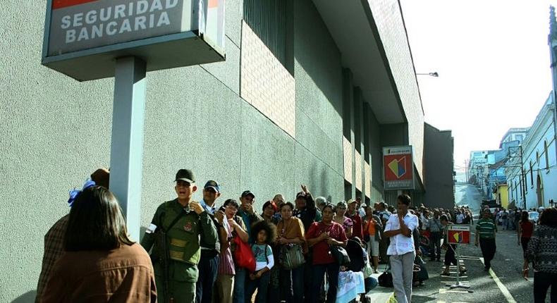 With Venezuela's government about to put millions of 100 bolivar bank notes out of circulation, people queue outside banks to deposit the notes to retain their value