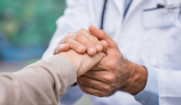 Close up of doctor hand reassuring her female patient at hospital. Closeup hands of medical doctor carefully holding patient's hands. Kind doctor giving real support for patient.