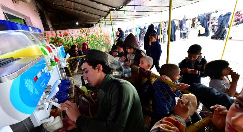 Children buy ice cream from a shop in a market at Al-Hol camp for displaced people in northeastern Syria