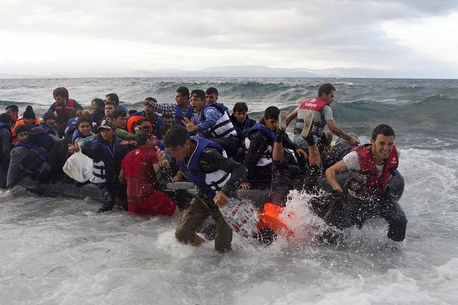 Refugees and migrants struggle to jump off an overcrowded dinghy on the Greek island of Lesbos, after crossing in rough seas from the Turkish coast