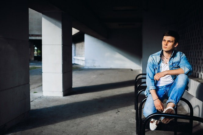 Brunette boy in jeans jacket poses outside