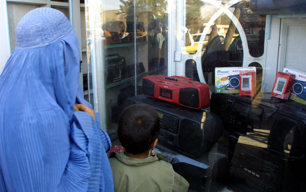 Afganka z synem przed sklepem ze sprzętem muzycznym