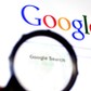 Hand holds Magnifying glass against Google homepage