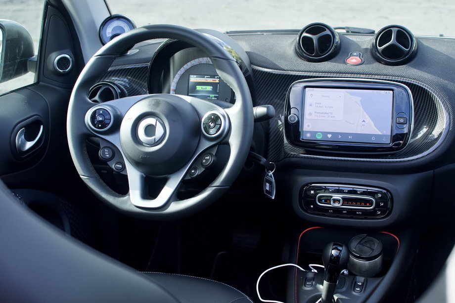 Smart ÈQ fortwo cabrio we wnętrzu nie urzeka. System na dotykowym ekranie jest dość archaiczny wizualnie i nie należy do najszybszych. Na szczęście obsługuje AndroidAuto i Apple CarPlay. 