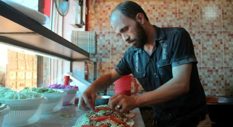 A Syrian man prepares food at the Ibad al-Rahman's Damascene Delicacies in the rebel-controlled northern city of Idlib on July 19