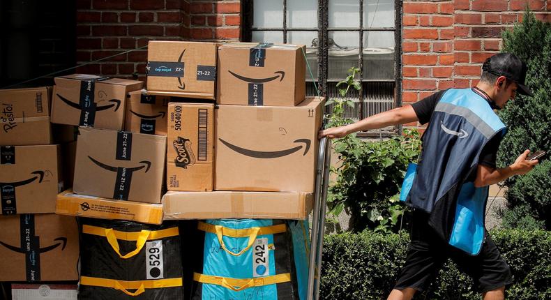 An Amazon delivery worker pulls a delivery cart full of packages during its annual Prime Day promotion in New York