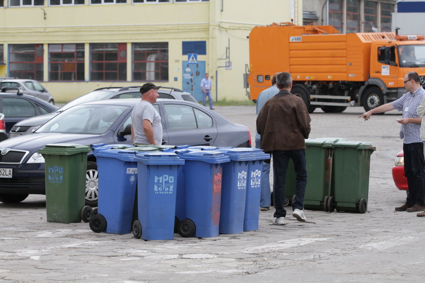 niebieskie pojemniki na śmieci stoją na placu