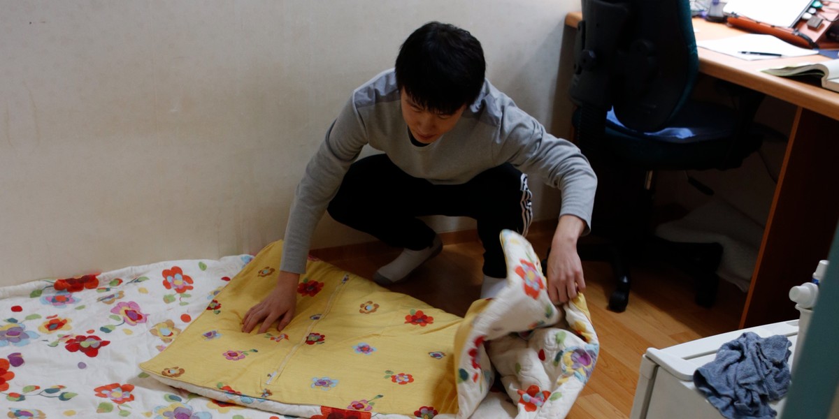 An exam applicant folds a quilt in his small room in one of the many private dorms that house students cramming for exams in a neighborhood of Seoul called Exam Village on December 13, 2012.