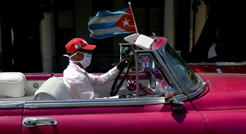 The driver of a vintage American car wears a face mask while taking tourists around Havana -- but Cuba is to close to visitors over the coronavirus outbreak