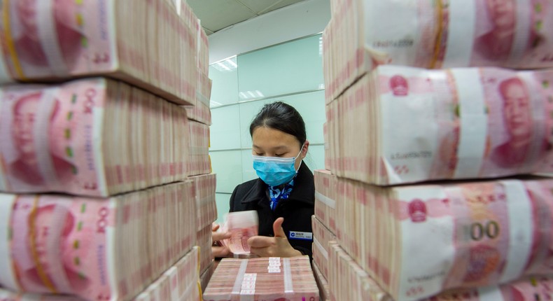 A clerk counts renminbi banknotes at a bank outlet in Haian city in east China's Jiangsu province.