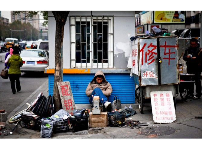Mężczyzna naprawiający rowery czeka na kolejnego klienta. Rozwój gospodarczy w Chinach wielu wyciągnął z biedy, ale spowodował też powstanie dużej przepaści finansowej pomiędzy zamożnymi i ubogimi. To może zagrozić stabilności kraju. Pekin, Chiny, 29 listopada 2011