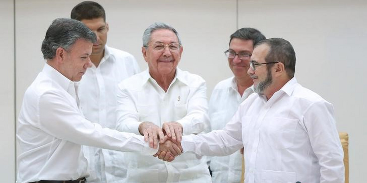 Cuba's President Raul Castro, center, stands as Colombia's President Juan Manuel Santos, left, and FARC rebel leader Rodrigo Londono, better known by the nom de guerre Timochenko, shake hands in Havana.