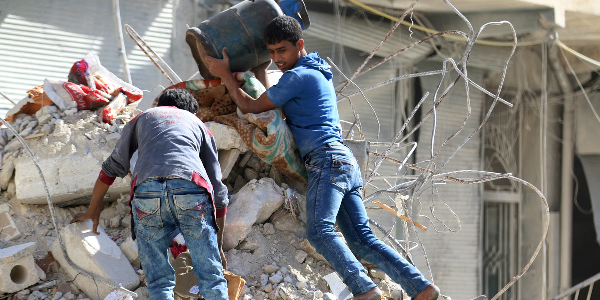 People remove belongings from a damaged site after an air strike in the rebel-held besieged al-Qaterji neighborhood of Aleppo, Syria.