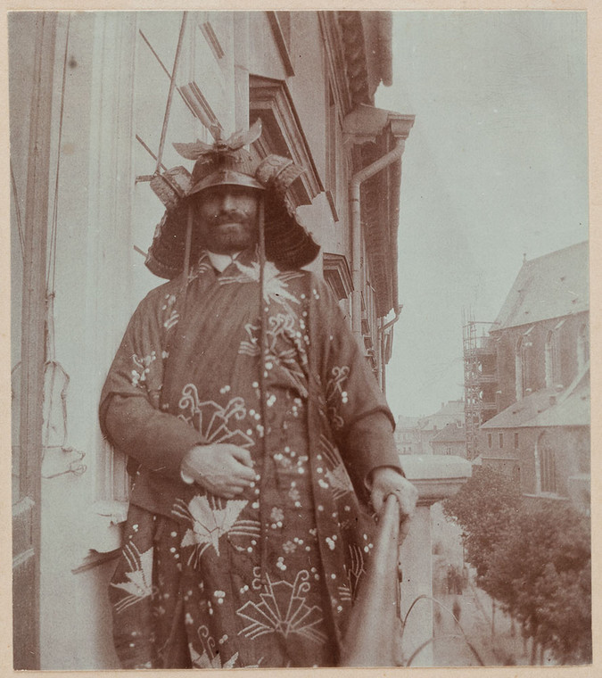 Feliks Jasieński w samurajskim hełmie i japońskim kimonie na balkonie mieszkania u zbiegu ul. Św. Jana i Rynku Głównego w Krakowie (1903-04)