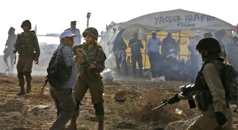 An Israeli soldier scuffles with a Palestinian journalist during a demonstration against the construction of Jewish settlements in the West Bank