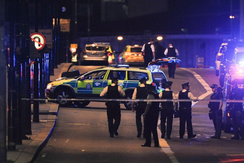 A police officer strecthes cordon tape accross the road near Borough Market after an attack left 6 p