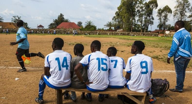 Local football players follow a match from the bench in Beni, DR Congo