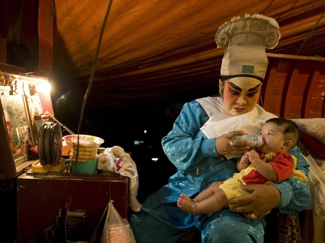 Chińska śpiewaczka operowa karmi dziecko kolegi występującego w spektaklu w Bangkoku