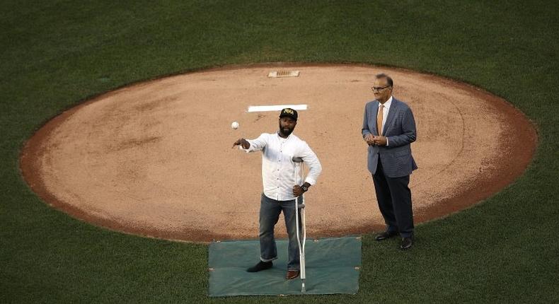 U.S. Capitol Hill special agent David Bailey (L), who was wounded in yesterday's shooting, throws out the first pitch at the Congressional Baseball Game in Washington, DC