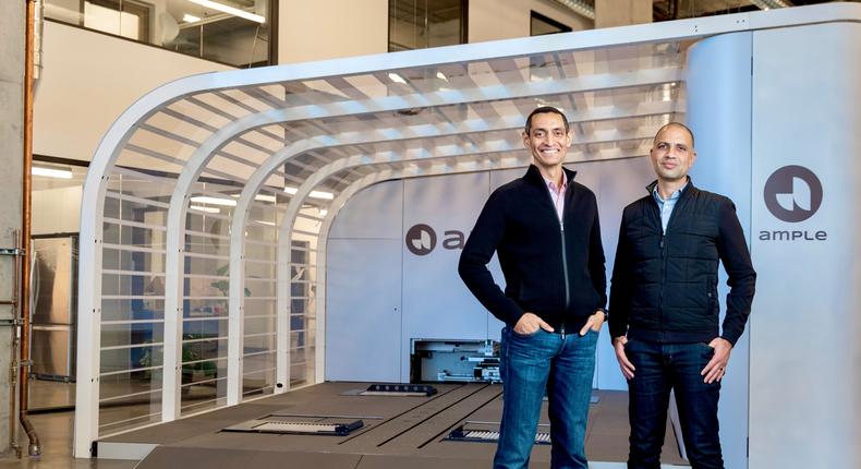 Founders Khaled Hassounah and John de Souza stand in front of a battery swapping station.
