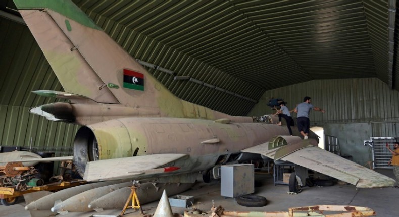 Fighters loyal to Libya's UN-recognised Government of National Accord (GNA) climb over a partially disassembled MiG 23 aircraft, after seizing Al-Watiya airbase  southwest of the capital Tripoli, on May 18, 2020.