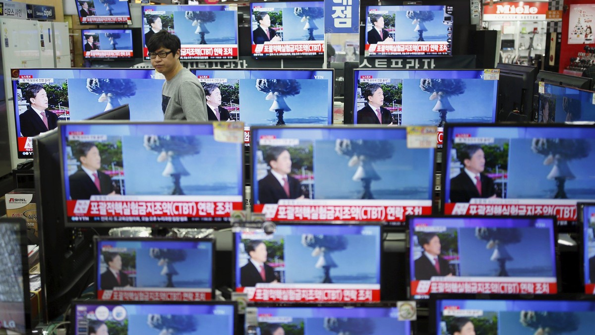 A sales assistant watches TV sets broadcasting a news report on North Korea's nuclear test, in Seoul