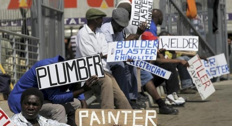 Men hold placards offering temporal employment services in Glenvista, south of Johannesburg, file. 