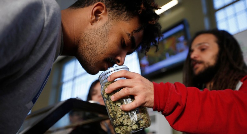 Volunteer Charlie Kirchheimer, 25, (R) holds out a jar of dried cannabis buds for Cyle Tahsini, 21, at the La Brea Collective medical marijuana dispensary in Los Angeles, California.