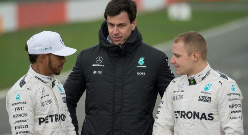 Mercedes drivers Britain's Lewis Hamilton (L) and Finland's Valtteri Bottas (R) pose with team chief Toto Wolff by the new 2017 season car at its launch at Silverstone near Towcester, central England on February 23, 2017