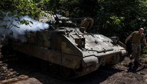 A soldier from Ukraine's 47th Mechanized Brigade runs past a US-made Bradley Fighting Vehicle as the engine is started at a secret workshop in a wooded area in the southern Zaporizhzhia Region.Ed Ram/For The Washington Post via Getty Images