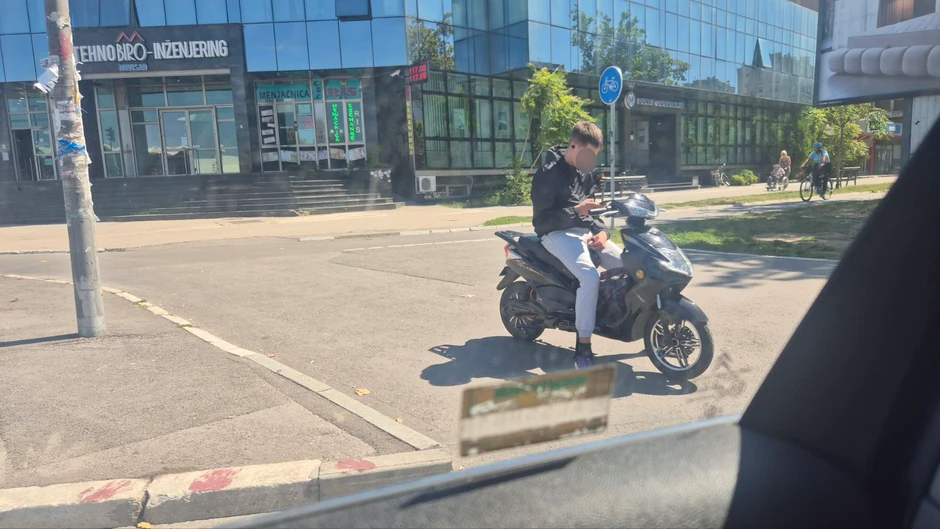 Mladić na električnom skuteru sa slušalicama na ušima