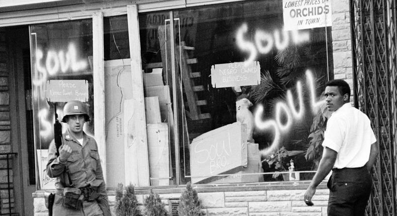 A National Guard officer passes the smashed window of a black-owned flower shop in riot-torn Newark, N.J., in this July 15, 1967, file photo.