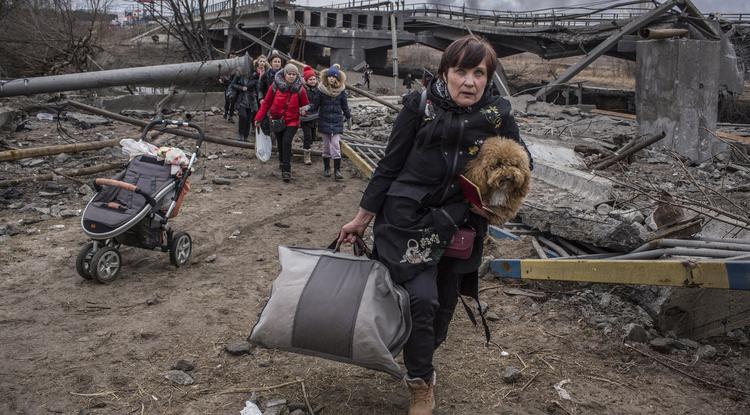 A Kijev közelében lévő Irpinyből menekülő emberek átkelnek egy orosz légicsapásban lerombolt híd alatt kialakított átkelőn, az Irpiny folyónál 2022. március 7-én.