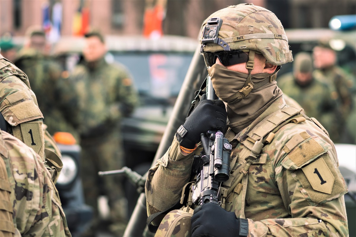 NATO, żołnierz w kominiarce i okularach trzyma broń w ręku