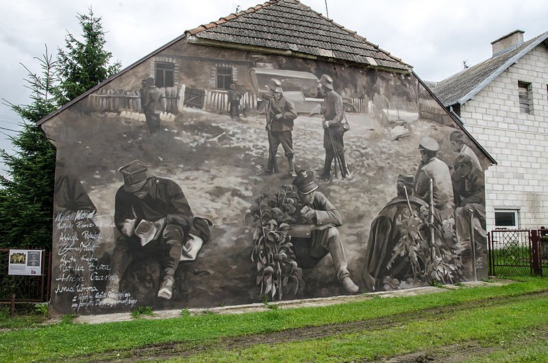 Mural na jednym z domów w Wiźnie przedstawiający żołnierzy kapitana Raginisa, jest on odwzorowaniem fotografii. Autor: Arkadiusz Zarzecki, licencja: CC BY-SA 3.0