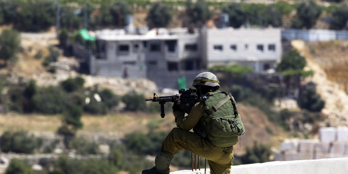 An Israeli soldier takes position during an operation to locate three missing teenagers, in the West Bank city of Hebron June 18, 2014.
