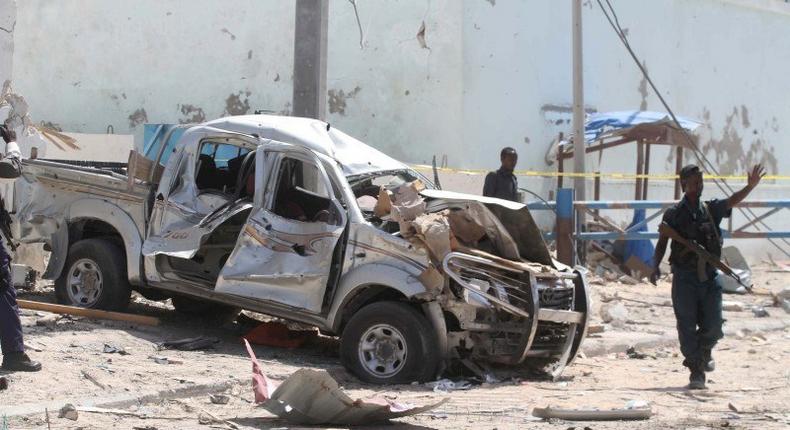 A policeman gives instructions near the wreckage of a car destroyed during a suicide bombing near the African Union's main peacekeeping base in Mogadishu, Somalia, July 26, 2016. REUTERS/Ismail Taxta