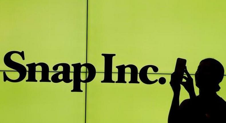 FILE PHOTO: A woman stands in front of the logo of Snap Inc. on the floor of the New York Stock Exchange in New York City