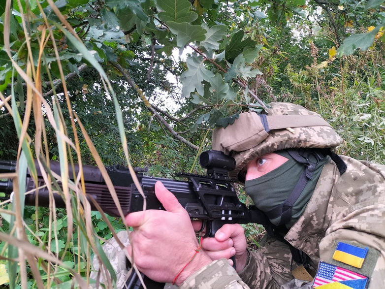 Ukraiński żołnierz batalionu obrony terytorialnej podczas szkolenia w obwodzie kijowskim, wyposażony w karabin automatyczny AK-74 z nowoczesnym celownikiem taktycznym wyprodukowanym w USA