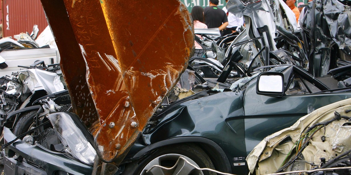 A backhoe operator demolishes a luxury vehicle.