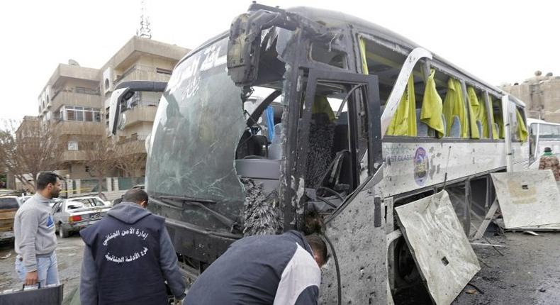 Syrian forensics experts examine a damaged bus following bomb attacks in Damascus' Old City on March 11, 2017