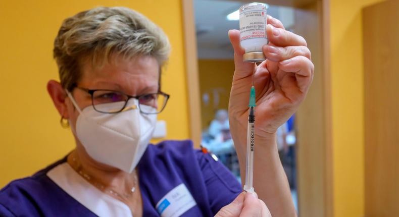 A woman measuring out a dose of COVID-19 vaccine.
