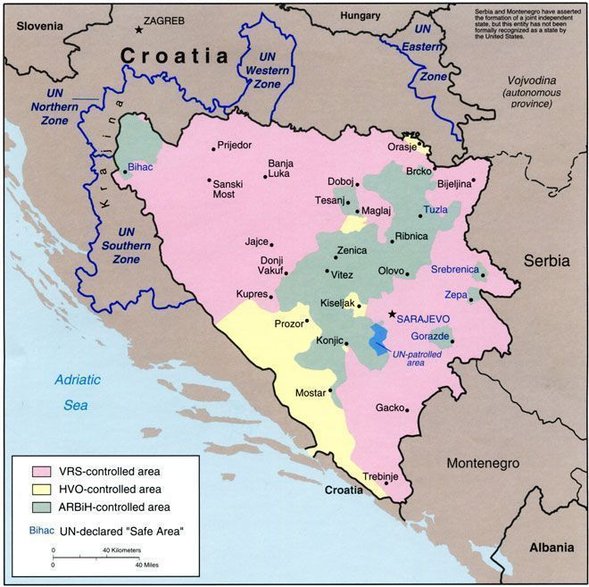 Kontrola terytorium w czasie wojny w Bośni i Hercegowinie, stan na marzec 1994 r. Kolor różowy - Serbowie, zielony - Bośniacy, żółty - Chorwaci. Na niebiesko zaznaczone "strefy bezpieczeństwa" ONZ (domena publiczna)