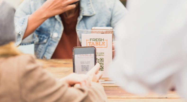 Women use a QR code to order lunch with their smart phone while outdoor dining.
