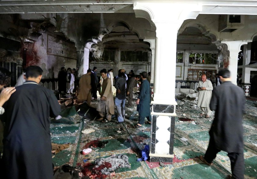 Afghan policemen and relatives inspect at the site of a suicide attack in Herat, Afghanistan