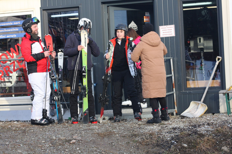 Turyści wychodzący z wypożyczalni nart