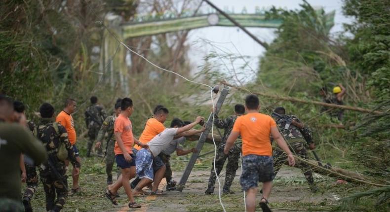 Rescue workers clear a road of debris and toppled electric posts caused by super Typhoon Mangkhut as they try to reach Baggao town