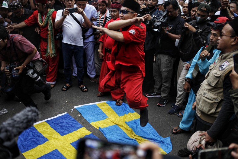 Indonezyjscy muzułmanie depczą szwedzką flagę podczas demonstracji przed szwedzko-duńską ambasadą w Dżakarcie w proteście przeciwko spaleniu Koranu przez szwedzko-duńskiego skrajnie prawicowego polityka Rasmusa Paludana w Szwecji, 30 stycznia 2023 r.